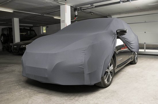 Zwarte auto met grijze, nauwsluitende autohoes, in een parkeergarage.