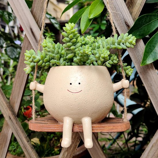 Lichtbeige bloempot in de vorm van een figuurtje met armen, benen en een gezichtje, zittend op een schommel.