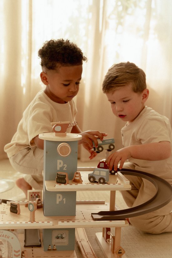 Twee kinderen spelen geconcentreerd met een houten parkeergarage en speelgoedauto's.