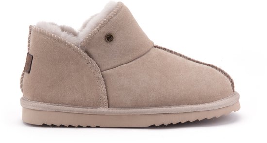 Taupe suède pantoffel met witte schapenvachtvoering, merklogo en profielzool.