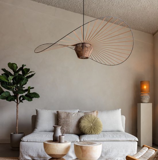 Koperbruine hanglamp in de vorm van een hoed boven een bank.