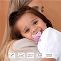 Baby lacht met paarse Difrax fopspeen met blaadjesprint in mond. 12+ maanden, natuurlijk, makkelijk te accepteren.