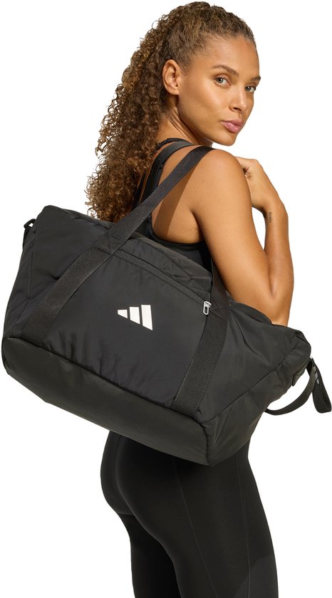 Vrouw met zwarte Adidas sporttas over de schouder gedragen.