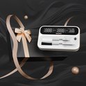Wit digitaal thermometerapparaat in een zwarte geschenkdoos met goudkleurige strik, op een luxe donkere achtergrond.