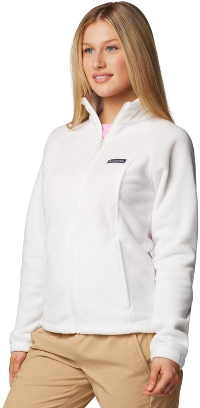 Een blonde vrouw in een witte fleece trui en een roze shirt, met een pet.