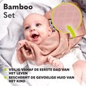 Een lachende baby met een zachtroze hydrofiele doek om zich heen geslagen.