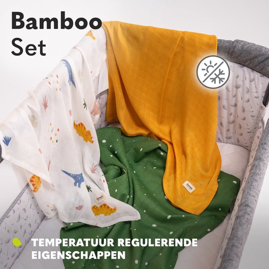 Drie hydrofiele doeken: wit met dino's, mosterdgeel en groen met stippen, in een babybedje.