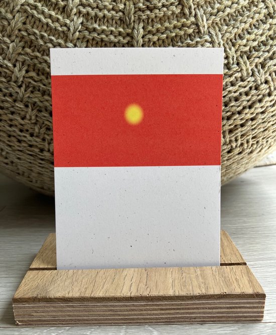 Een witte kaart met een rode band met een gele stip, boven een witte onderkant, in een houten display.