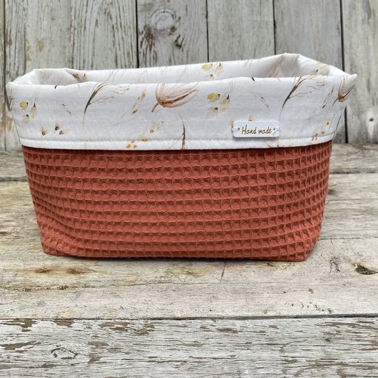 Wafelstof mandje in terracotta met subtiele, delicate bloemenprint aan de binnenzijde. Label 'Hand made'.