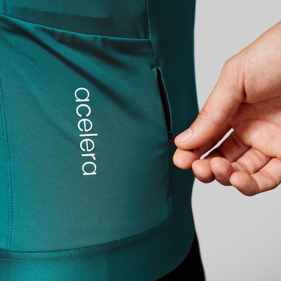 Detail van turquoise wielershirt met 'acelera' logo en een ritsvakje.