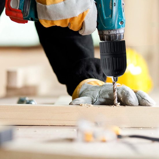 Gele handschoenen gebruiken boorkop om in hout te boren.