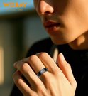 Mannelijke hand met zwarte ring met een gebogen lijn erop.