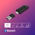 Zwarte USB-C dongle met USB-A adapter en Bluetooth-logo, met compatibiliteitsiconen voor pc, Mac, PlayStation en Switch.