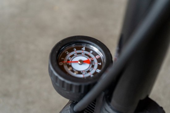 Close-up van een zwarte fietspomp met een drukmeter. De wijzer staat op 4.