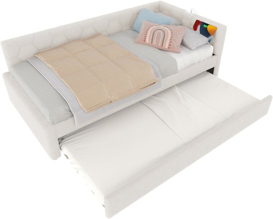 Witte slaapbank met uitschuifbaar bed, hexagonaal patroon op de rugleuning, met dekbed en kussens.