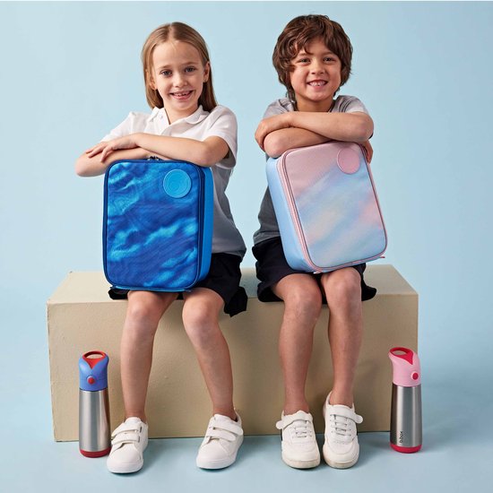 Deux enfants, un garçon et une fille, assis avec des sacs à lunch. Fille avec sac bleu, garçon avec sac rose et bleu. Les sacs ont un imprimé tie-dye.