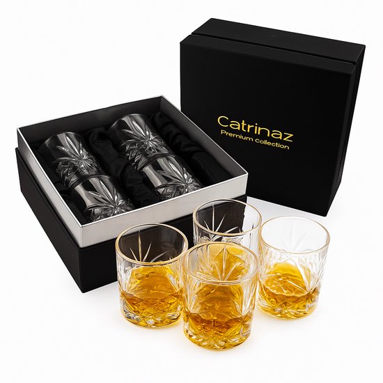 Une boîte cadeau noire ouverte avec le logo Catrinaz, contenant quatre verres à whisky, et quatre verres remplis de liquide ambré à côté.
