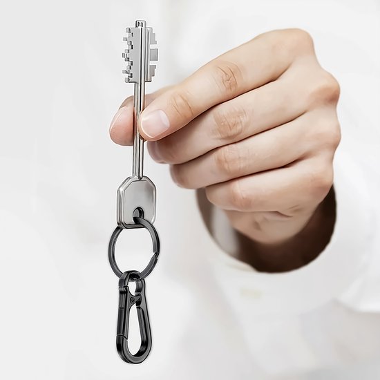 Hand houdt een sleutel met een zwarte karabijnsluiting en sleutelring vast.