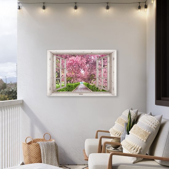 Een schilderij van een open raam met uitzicht op een pad omringd door bloeiende kersenbomen, opgehangen aan een buitenmuur naast zitmeubels.