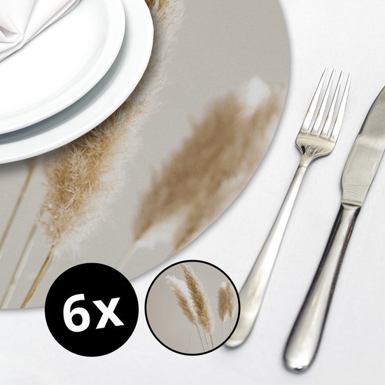 Une table dressée avec des assiettes blanches et des couverts, sur laquelle repose un set de table rond à motif de plumes.