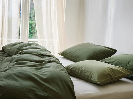 Donker olijfgroen dekbedovertrek van katoensatijn, casual gedrapeerd op een bed met vier bijpassende kussens.