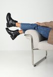 Mannequin portant des bottines noires à imprimé crocodile, fermeture éclair et boucle, avec un jean bleu.