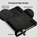 Close-up van zwart notitieboek met "Soft cover vegan leer", "Sluitelastiek" en "Leeslint".