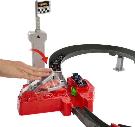 Hand gebruikt een F1 lanceerder op de Hot Wheels racebaan met raceauto's in de startpoort.
