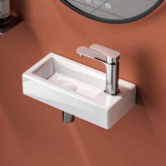 Lavabo blanc en céramique avec robinetterie chromée, monté au mur.