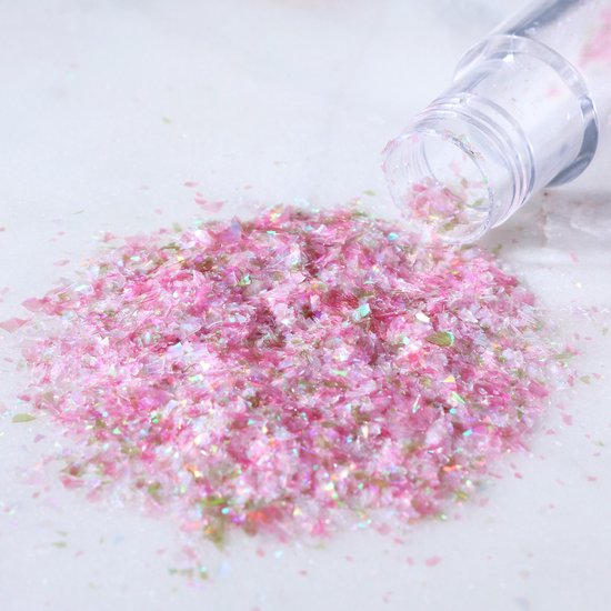Roze eetbare glitters in vlokvorm, op een witte ondergrond.