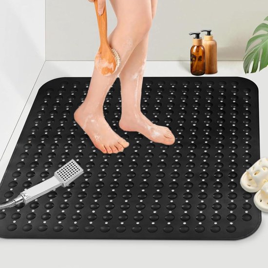 Zwarte antislip douchemat met ronde noppen, een persoon die zijn benen schrobt met een borstel.