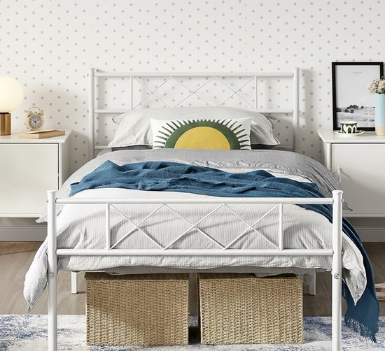Wit metalen bedframe met diamantpatroon hoofdbord en voetbord, lichte achtergrond met grijze stippen.