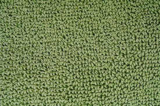 Detail van de lichtgroene badstof met lusjes, die textuur en zachtheid benadrukken.