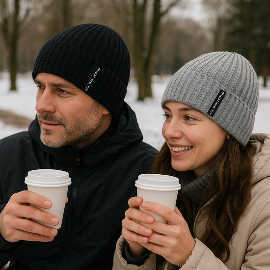 Een man met een zwarte gebreide muts en een vrouw met een grijze gebreide muts houden koffie vast.