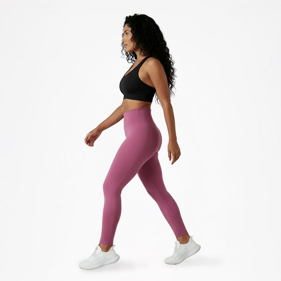 Vrouw loopt in roze sportlegging met hoge taille en witte sneakers.