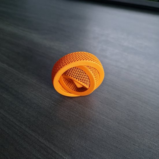 Oranje gyro spinner met een open, rasterachtig ontwerp op een donkergrijs bureau.