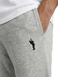 Detail van een lichtgrijze joggingbroek met zwart logo op de linkerheup.