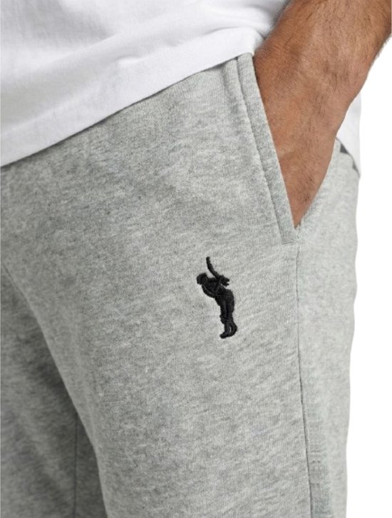 Detail van een lichtgrijze joggingbroek met zwart logo op de linkerheup.