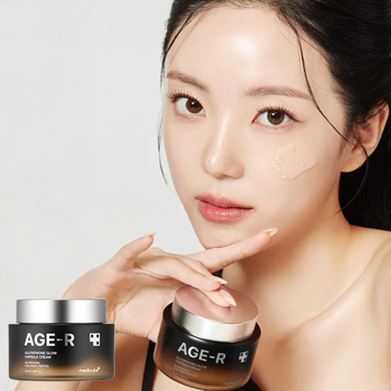 Een vrouw met de AGE-R Glutathione Glow Capsule Cream, met een potje ernaast en crème op haar wang.