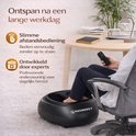 Zwart voetmassageapparaat van Phonergy in een kantooromgeving. Een persoon bedient het met een afstandsbediening.
