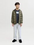 Jongens in een donkerblauw T-shirt met "JACK & JONES" opdruk, gedragen onder een kaki jas.