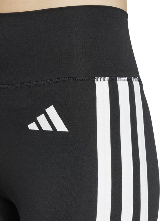 Close-up van de zijkant van een zwarte sportlegging met witte Adidas strepen en logo.
