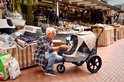 Man voert hond in beige InnoPet buggy op een markt.
