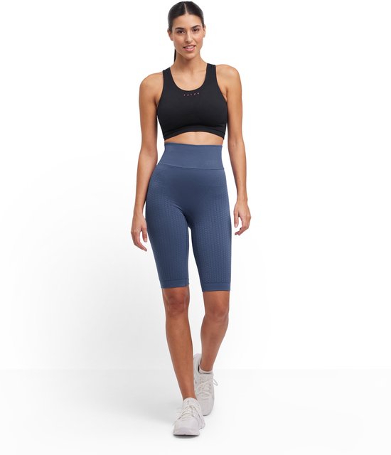 Model van voren gezien in blauwe, nauwsluitende capri-legging met textuur en een zwarte sportbeha.