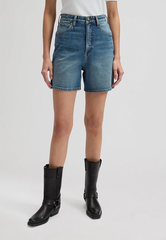Een vrouw draagt een spijkerbroek met wijde pijpen en zwarte cowboylaarzen.