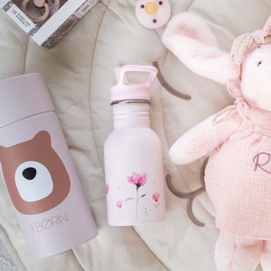 Roze schoolbeker met bloesemprint en een roze bewaarbox met berenprint, naast een knuffel.