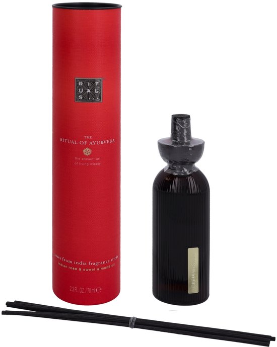 Rode kartonnen verpakking voor 'The Ritual of Ayurveda' geurstokjes, naast een donkere glazen diffuser.