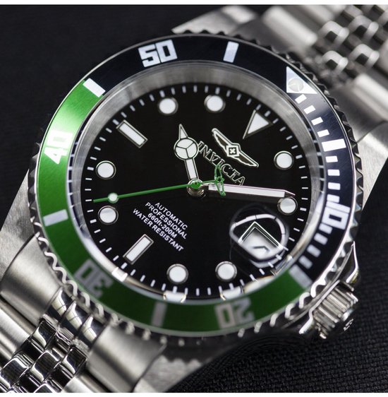 Gedetailleerde weergave van een herenhorloge met zwarte wijzerplaat, groene lunette en zilverkleurige band.
