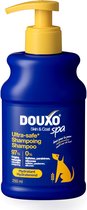 Donkerblauwe fles met gele pompdispenser en dop. Tekst: DOUXO Ultra-safe Shampooing. Met gele hondensilhouet.