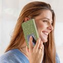 Vrouw met een groen telefoonhoesje met bladerpatroon aan de telefoon.